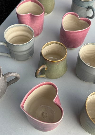 Billede af keramik krus og kopper på et bord, hvor flere af krusene er formet som et hjerte