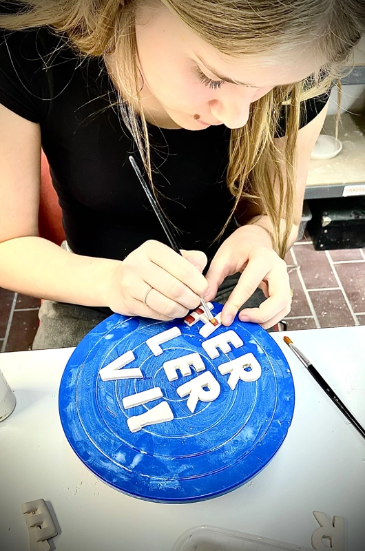 Unge pige der malet keramik bogstaver i keramikværksted. 